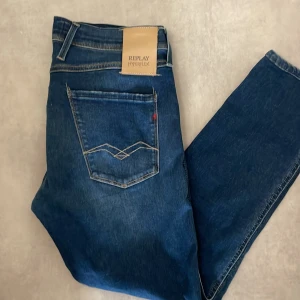 Blå jeansbyxor från Replay - Snygga blå jeansbyxor från Replay i modellen Anbass. De har en slim fit och är tillverkade i ett stretchigt material för extra komfort. Klassisk femficksdesign med dragkedja och knapp framtill.