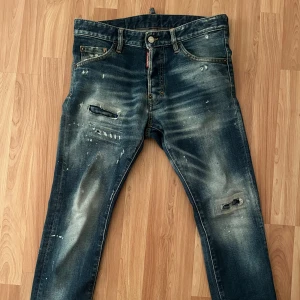 Dsquared2 Jeans - Jeans från Dsquared2 med slitningar och en unik design. Byxorna är av modellen ”Cool Guy”  Perfekta för en trendig och avslappnad stil. Skick 8/10, ny pris ca 4900. Pris kan diskuteras. Storlek 44 men passar mig som är ca 170. Hålen går inte igenom