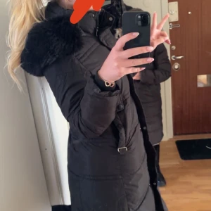 Svart dunjacka med pälshuva - Snygg svart dunjacka med pälskantad huva.  Jackan är i storlek M 