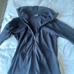 Svart tränings kofta från Gina Tricot - Säljer en svart jacka från Gina Tricot med dragkedja framtill. Jackan har långa ärmar och en hög krage, perfekt för gym eller för en fin outfit . Enkel och stilren design som passar till det mesta.