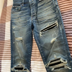 Blå jeans med slitningar från Amiri - Snygga blå jeans från Amiri med coola slitningar och hål för en trendig look. De har en klassisk femficksdesign och en bekväm passform. Perfekta för att ge din outfit en edgy touch. Pris kan diskuteras 