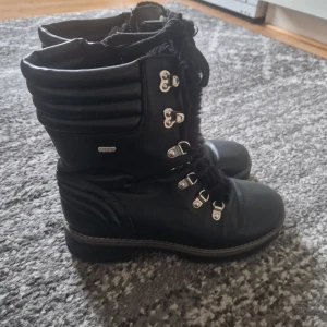 Svarta boots från Esprit - Snygga svarta boots från Esprit med snörning och dragkedja. De har en vadderad design upptill och robust sula, perfekt för kyligare väder. Tillverkade i syntetmaterial med en stilren look.