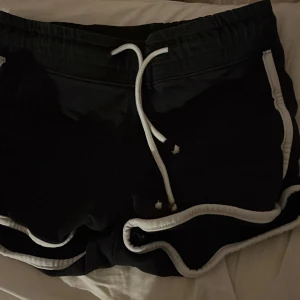 Svarta shorts med vita detaljer - Snygga svarta shorts med vita kantdetaljer och snörning i midjan. Perfekta för en avslappnad stil.