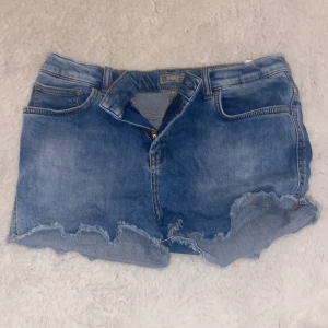 Blå jeansshorts från LTB💋 - Säljer ett par coola blå jeansshorts från LTB med fransiga kanter. Perfekta för sommardagar! De har en klassisk femficksdesign och en knappgylf.