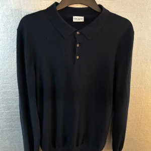 Mörkblå pikétröja från JOHN HENRIC - Snygg och stilren mörkblå pikétröja från John Henric med långa ärmar och knappar framtill. Perfekt för en elegant och avslappnad look. Matetialet är superskönt och tröjan är i nyskick. Passar M