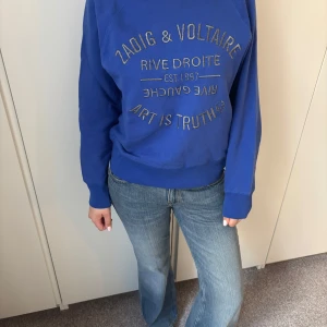 Blå tröja från Zadig & Voltaire - Snygg blå tröja från Zadig & Voltaire med tryck framtill. Perfekt för en avslappnad stil. Tröjan har långa ärmar och rund halsringning. Nypris är 2100kr