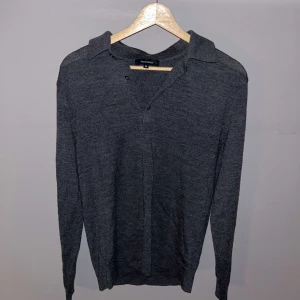 Grå/svart tröja från Paul & Friends - Säljer en riktigt skön grå/svart tröja från Paul & Friends. Tröjan har en klassisk krage och knappar vid halsen. Perfekt för en avslappnad och snygg look. Storlek M men passar S