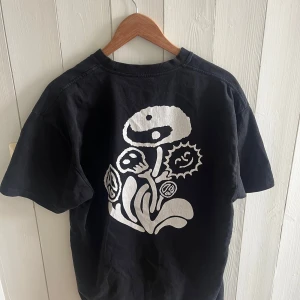 Svart t-shirt från Polar - Säljer en svart t-shirt från Polar med ett coolt vitt tryck av en blomma på baksidan och Polar-loggan på framsidan. T-shirten är kortärmad och perfekt för en avslappnad stil. Skön och stilren design!