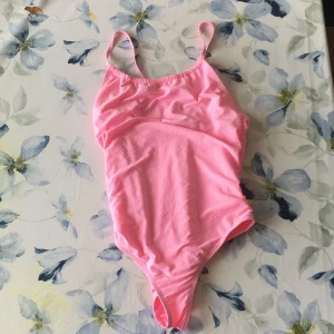 Rosa baddräkt med mönster - Snygg rosa baddräkt med subtilt mönster och smala axelband. Perfekt för sommarens badäventyr. Materialet är mjukt och bekvämt, vilket gör den idealisk för en dag på stranden eller vid poolen. Baddräkten är aldrig använd då den är för stor. 