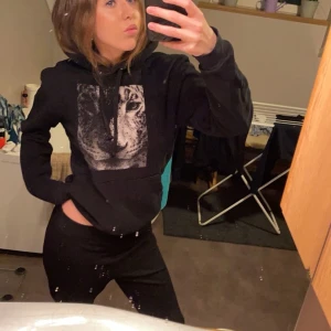 Svart hoodie med leopardtryck - Snygg svart hoodie med ett stort leopardtryck på framsidan. Hoodien har en klassisk passform. Den är dock ganska sliten på själva trycket, därav priset.🩷Ordinariepris ca 566 kr