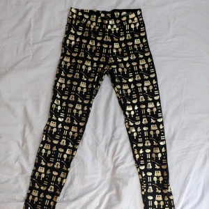 Svarta leggings med guldmönster Mickey Mouse, Disney, HM - Snygga svarta leggings med ett coolt guldmönster Mickey Mouse som ger en unik look. Perfekta för att sticka ut med stil. De har en tight passform och är gjorda i ett bekvämt material, 95% bomull och 5% elastan. Mickey Mouse, Disney, HM