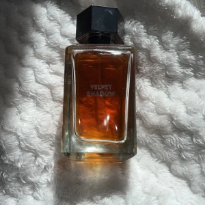 Velvet Shadow Parfym 100 ml  - Elegant parfymflaska med en djup bärnstensfärgad vätska. Flaskan har en stilren, fyrkantig design med en svart, geometrisk kork. Namnet 'Velvet Shadow' är tryckt på framsidan. Jag skulle säga 80% är kvar av flaskan men du själv kan avgöra på bilden😍😍🙌🏼🍓