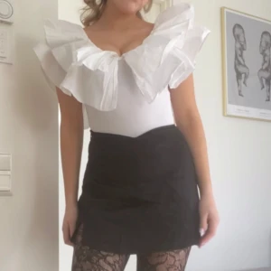 Vit volangbody från Zara - Säljer en snygg vit body med stora volanger runt halsringningen. Sitter bra på mig som har S vanligtvis!💘💘💘