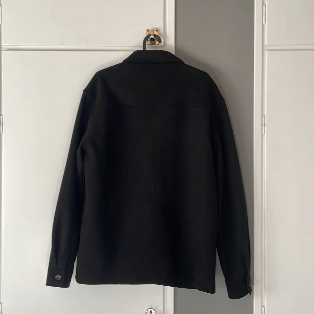 Snygg svart overshirt med knappar och två bröstfickor. Knappt använd pga för stor. Storlek M passar L också. Nypris: 559kr. Skick 9/10, inga defekter. Hör av er vid frågor! . Takit.