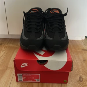Nike Air Max 95 sneakers i svart och grå - Snygga Nike Air Max sneakers i svart och grå med orange detaljer. Helt nytt jag har inte använt den ute normalpris 2500kr
