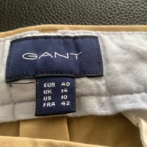 Beige chinos  - Säljer ett par stilrena beige chinos. Byxorna har en regular cropped passform och är perfekta för en avslappnad men ändå snygg look. De har knappar bak och en klassisk design som funkar till många tillfällen. Helt oanvända. Byxorna är Strl 40 och ja vad finns det och säga mer😅 Priset går självklart och diskuteras vid snabba affär!☺️