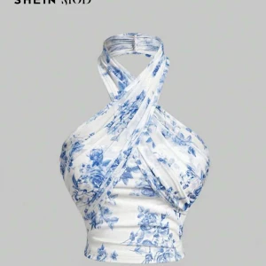 Vit och blå halterneck topp med blommigt mönster från SHEIN - Säljer en snygg halterneck topp från SHEIN i vitt med blått blommigt mönster. Helt oanvänd endast testad en gång, prislapp kvar. Toppen har omlott-design och är ärmlös med en croppad passform. Perfekt för sommardagar och fester!