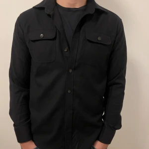 John Henric Overshirt - En snygg mörkblå overshirt som jag enbart säljer för att den har blivit för liten för mig. Använd men fortfarande i bra skick utan defekter.