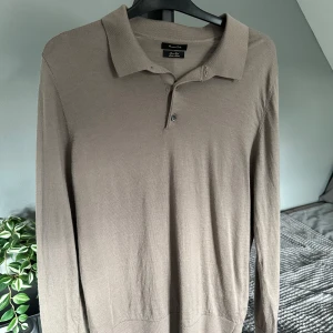 Beige långärmad pikétröja från Massimo Dutti - Säljer en stilren beige långärmad pikétröja från Massimo Dutti i merinoull. Storlek L. Köpt second hand men har inte använt den själv. 