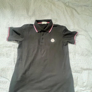 Svart piké t-shirt från Moncler - Säljer en svart piké t-shirt från Moncler perfekt nu när sommaren kommer använd 1 gång storlek m men kan kanske också passa s