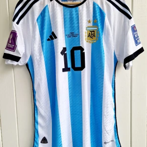 Leo Messi - Argentina VM-final 2022 - Säljer en klassisk fotbollströja, Messis argentinska VM-finaltröja från 2022. Tröjan är en reprint i nyskick med emblem och patchar av högsta kvalité. Storlek: XL. Tröjan är en player version. Tajt i storleken så storleken motsvar mer large. Slim.