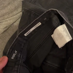  Replay jeans  - Säljer ett par svarta Replay jeans med klassisk femficksdesign och snygga detaljer på bakfickan. Byxorna har en svart läderpatch med Replay-logga och stängs med dragkedja. Midjemått W29 och längd L32. 