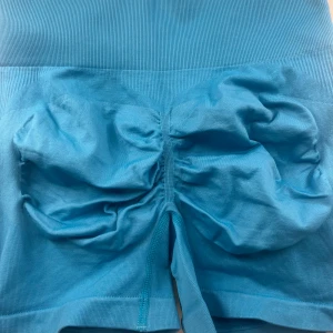 Blå sömlösa träningstights-shorts - Säljer ett par blå sömlösa shorts i stretchigt material med scrunch-detalj bak. Perfekta för träning. Aldrig använda!