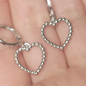  Helt nya Silverfärgade hjärtformade örhängen - Säljer ett par  helt nya söta örhängen i silverfärg med hjärtformade hängen. Hjärtana har en pärlad kant som ger en fin detalj. Perfekta för dig som gillar stilrena och romantiska smycken.