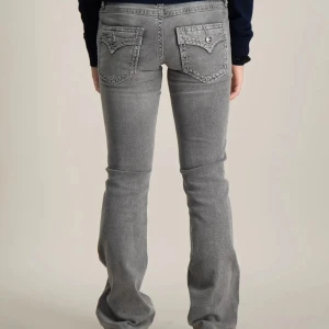 Grå bootcut jeans med broderade bakfickor - Säljer ett par grå jeans med bootcut passform och snygga broderade detaljer på bakfickorna. Jeansen har dragkedja och knapp framtill samt klassiska fickor. Perfekta för dig som gillar en lite utsvängd stil. original pris 400kr men säljer för 200kr🩷 faktiskt aldrig andvända