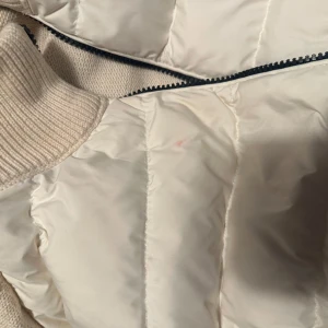 Moncler cardigan  - Säljer en snygg vit dunjacka från Moncler med stickade partier i krage och axlar. Jackan har dragkedja framtill och klassisk Moncler-logga på bröstet och på axeln. Den är i 6/10 skick det behövs en kemisk tvätt inte säkert att det går bort men borde göra de, och moncler logan skulle behövas sy och fixas. Men för det priset är det en steal. 
