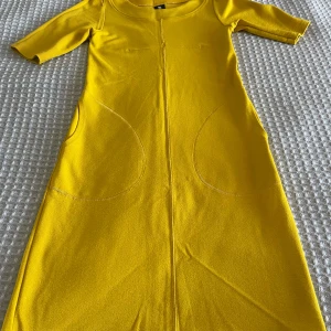 Gul klänning från Nanso - Säljer en vintage solgul klänning från Nanso i storlek XS. Klänningen har trekvartsärm, rund halsringning och praktiska fickor framtill. Den är i mjukt material och har en rak, enkel passform som känns både modern och bekväm.