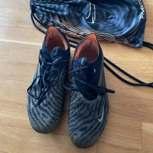 Nike Phantom elite - Säljer ett par Nike Phantom elite fotbollsskor i svart och orange med snörning och rund tå. Skorna är i använt skick, men dess funktion är ändå bra. Skorna kommer även med en bag. 