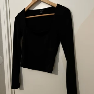 Svart långärmad topp  - Säljer en svart långärmad topp med fyrkantig ringning. Jätte fin med skönt material