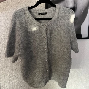 Grå stickad kofta från Gina Tricot - Mysig grå stickad kofta från Gina Tricot med korta ärmar och rund halsringning. Koftan är så sjukt mysig och mjuk. Perfekt året runt!