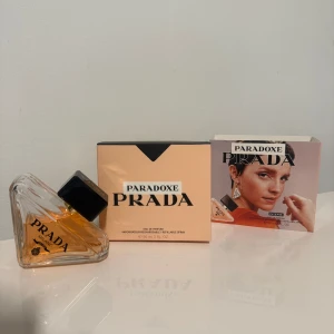 Prada Paradoxe Eau de Parfum 90ml - Prada Paradoxe Eau de Parfum i en unik, trekantig glasflaska med svart fyrkantigt lock och guldig detalj. Parfymen har en varm bärnstensfärgad vätska och kommer i en stilren ljusrosa kartong. Flaskan rymmer 90 ml och är påfyllningsbar.