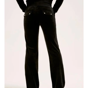 Svarta velourbyxor Juicy Couture XL - Svarta mjukisbyxor från Juicy Couture i lyxig velour. Byxorna har bred resår i midjan med snörning, stora fickor fram och bak med lock och silverfärgade knappar. Klassisk logga broderad på ena fickan. Perfekta för en chill och trendig look. Säljs då de blivit förstora och inte anvädns längre, i superfint skick. Pris kan diskuteras!⭐️