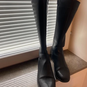 Medelhöga boots i skinn, pris kan diskuteras  - Stilrena svarta stövlar i äkta skinn med rund tå och platt sula. De har dragkedja på insidan för enkel påtagning och en klassisk, tidlös look som funkar till många outfits. Perfekta för höst och vinter. Inte använt särskilt många gånger, pris kan diskuteras, storlek 38-39