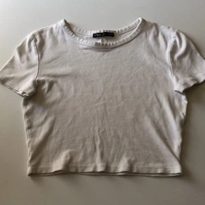 Vit croppad topp från Zara - Enkel och stilren vit croppad topp från Zara. Modellen har rund halsringning och korta ärmar, perfekt till jeans eller kjol. Mjuk bomullskänsla och klassisk passform som funkar till många olika looks.