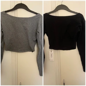 2 croppade långärmade toppar Dazy - Två stilrena croppade toppar från Dazy, en i svart och en i grått. Båda har lång ärm och bred, något båtformad halsringning. Perfekta att matcha med höga jeans eller kjol. Mjukt och stretchigt bomullsmaterial som sitter snyggt och bekvämt.