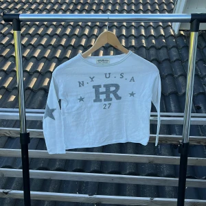 Vit långärmad tröja Hampton Republic - Vit långärmad tröja från Hampton Republic med grå tryckdetaljer framtill och stjärna på ena ärmen. Tröjan har rund halsringning och är i mjuk bomull, perfekt för en chill och sportig look.