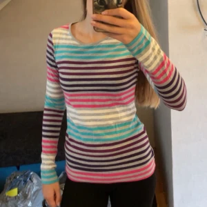 Randig långärmad tröja - Säljer en färgglad långärmad tröja från Lindex i storlek 170. Tröjan har horisontella ränder i lila, turkos, rosa, grått och vitt. Den är i mjuk bomull och har en klassisk rund hals. Perfekt för dig som gillar färg och mönster! Kan användas som vanlig tröja eller pyjamas! Matchar de turkosa tightsen som även ligger ute!🌈