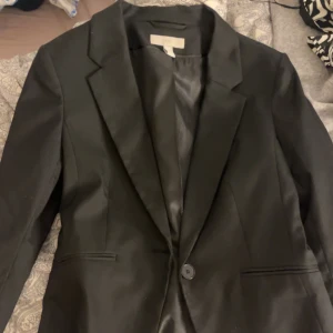 Svart kavaj  - Klassisk svart kavaj från H&M med enkelknäppning och smala slag. Snygg och stilren modell med två fickor framtill och helfodrad insida. Perfekt för en clean och uppklädd look.
