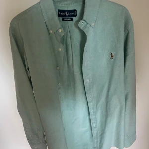 Ralph lauren skjorta - Säljer en grön Ralph lauren skjorta svin snygg skjorta färgen är unik och perfekt till sommaren. Riktigt bra skick enbart en liten fläck på sista bilen syns knappt och tvättas bort lätt. 