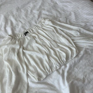 Vit offshoulder blus från Bik Bok - Supersöt vit blus från Bik Bok med offshoulder-modell och långa puffiga ärmar. Toppen har resår både upptill och nertill för en snygg passform och är gjord i ett lätt, luftigt tyg som känns perfekt för varmare dagar.