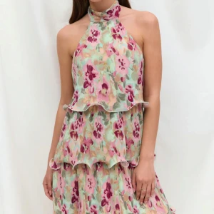 Blommig halterneckklänning med volanger - Superfin kort klänning med blommigt mönster. Klänningen har halterneck med knyt i ryggen. Perfekt för sommaren när du vill sticka ut lite extra😊nyskick då den endast är testad!