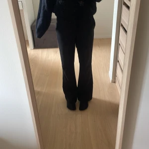 Svarta kostymbyxor från Lindex  - Svarta kostymbyxor från Lindex i klassisk modell med raka ben och hällor för bälte. Byxorna har sidfickor och är tillverkade i ett slätt tyg som ger en stilren look. Perfekta för dig som gillar en clean och enkel stil.🥰