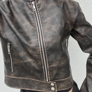 Brunsvart skinnjacka med dragkedja  - Säljer min nya brun/svarta skinnjacka från Nelly. Den har dragkedjor framtill, vid fickor och ärmen. Jackan är i en kort modell och har även knappar nedtill. Den är köpt för 599kr men den är använd några gångar, därav priset. Hör av dig vid frågor, svarar oftast inom 24h 💕