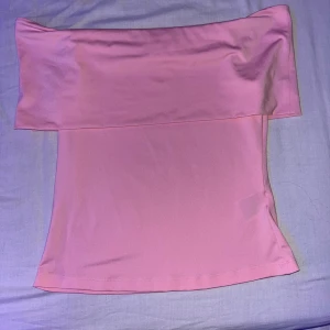 Ljusrosa bandeau tubtopp - Säljer en ljusrosa bandeau tubtopp med axelbandslös design. Toppen har en enkel och clean look med mjukt, stretchigt material som sitter tight mot kroppen. Perfekt för dig som gillar minimalistisk stil och vill ha en topp som sticker ut med sin färg. Pris kan diskuteras🤗