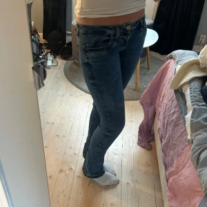LTB bootcut jeans - Säljer ett par blå bootcut jeans från LTB, modell Valerie. Jeansen har låg midja, klassiska bakfickor med broderade detaljer och råa, fransiga benslut. Tillverkade i stretchig denim för en tight och bekväm passform.