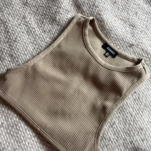 Beige ribbad linnetopp Missguided - Säljer en beige ribbad linnetopp från Missguided. Toppen är ärmlös med rund halsringning och croppad passform